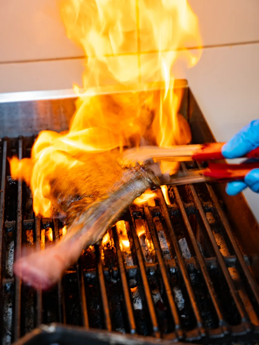 Steak being flame grilled in the Le Pavillon kitchen