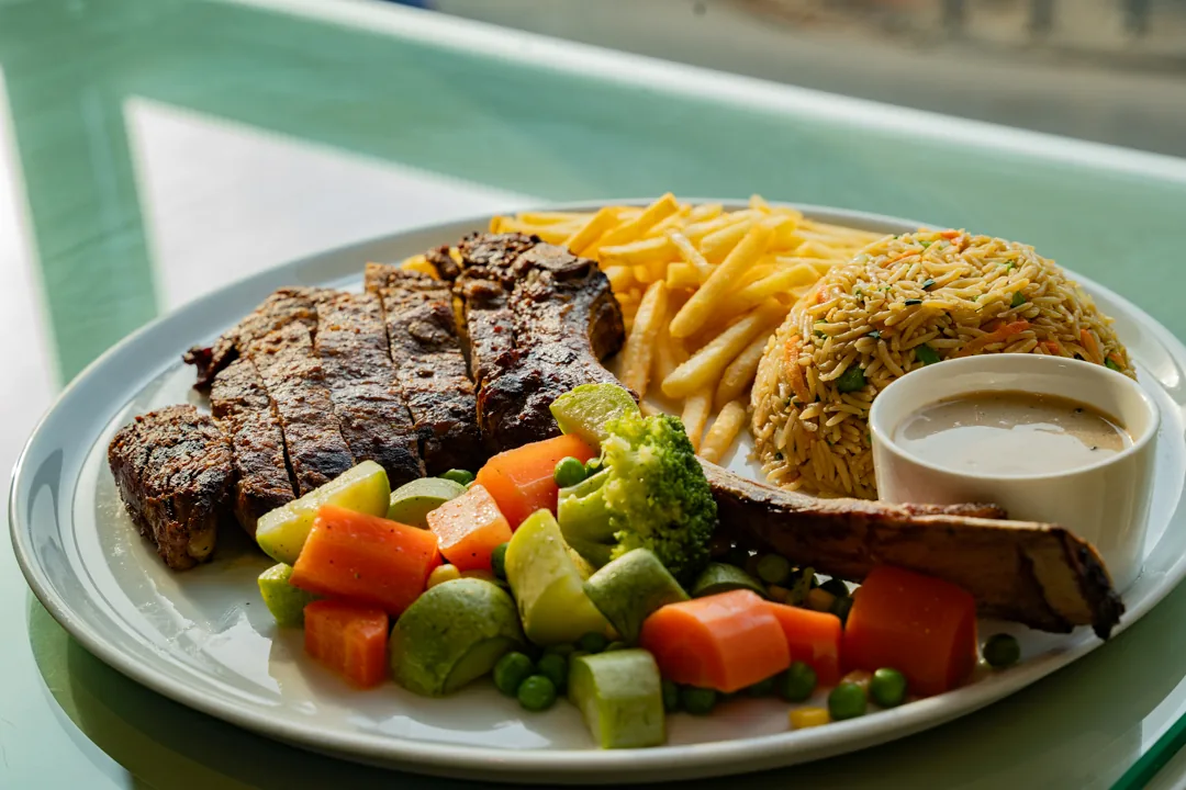 Tomahawk steak served with vegetables, rice and fries